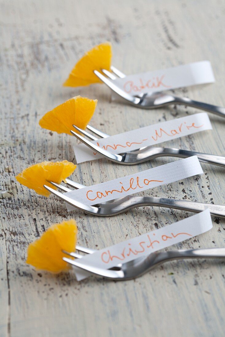 Namenschildchen mit Orangen auf Kuchengabeln