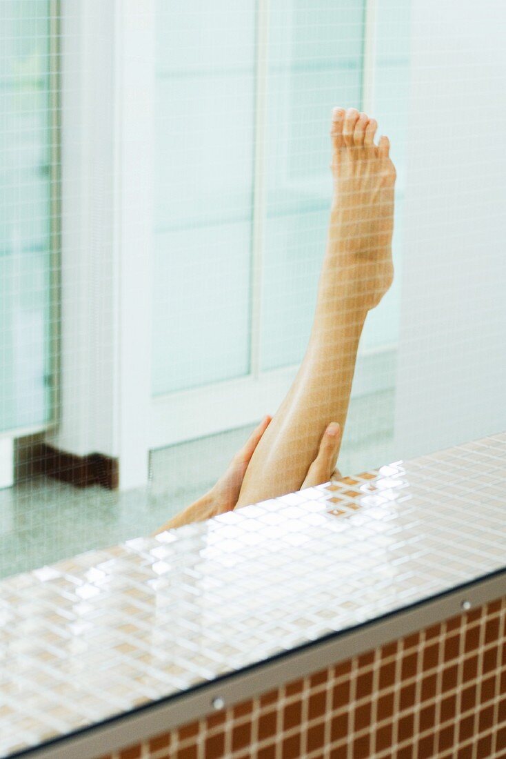 Woman holding up bare leg, cropped view