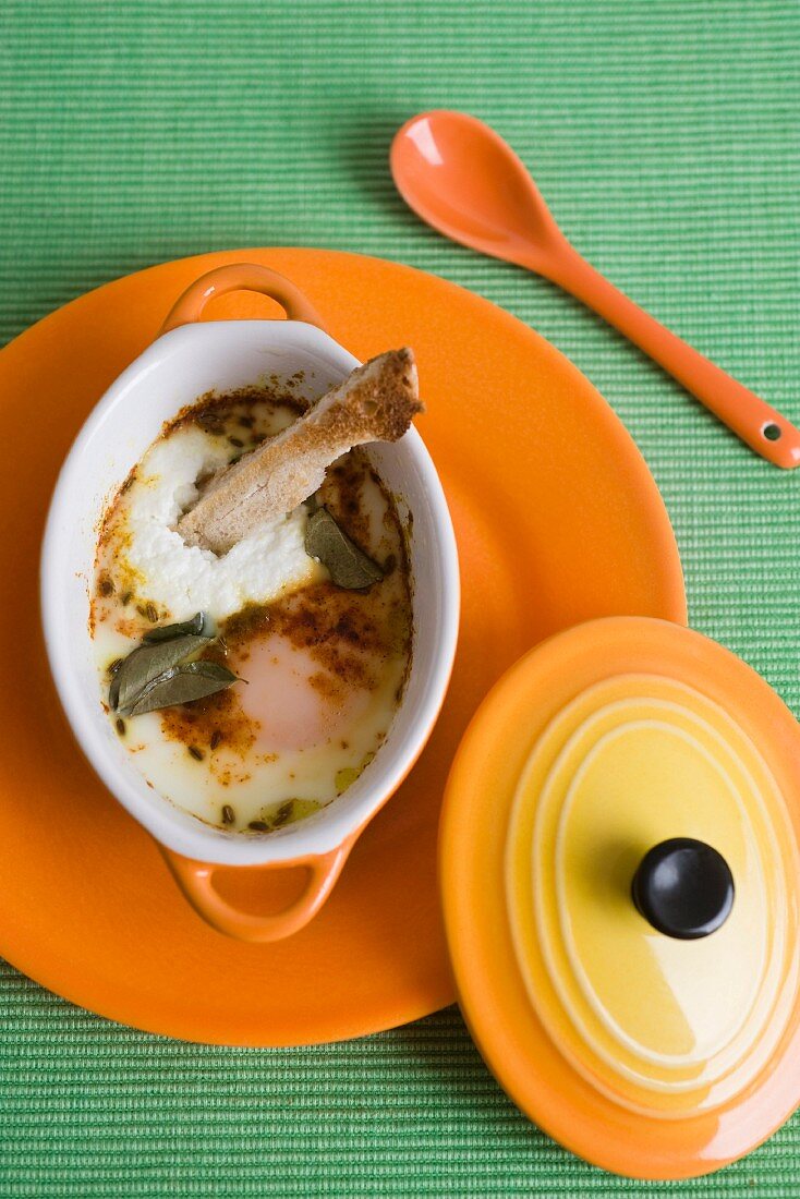 Oeufs cocotte with herbs, spices and bread sticks