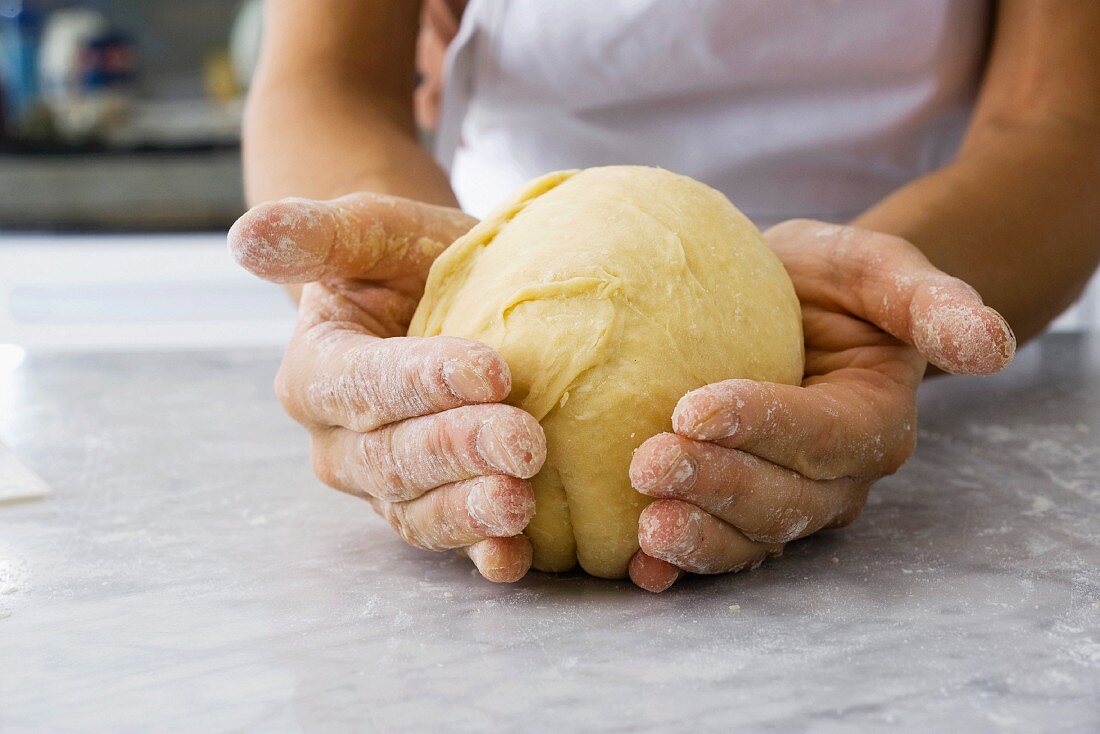 Hands shaping a ball of dough