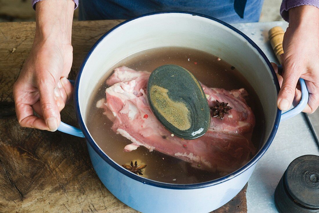 Hands holding a saucepan filled with Oriental chicken stock
