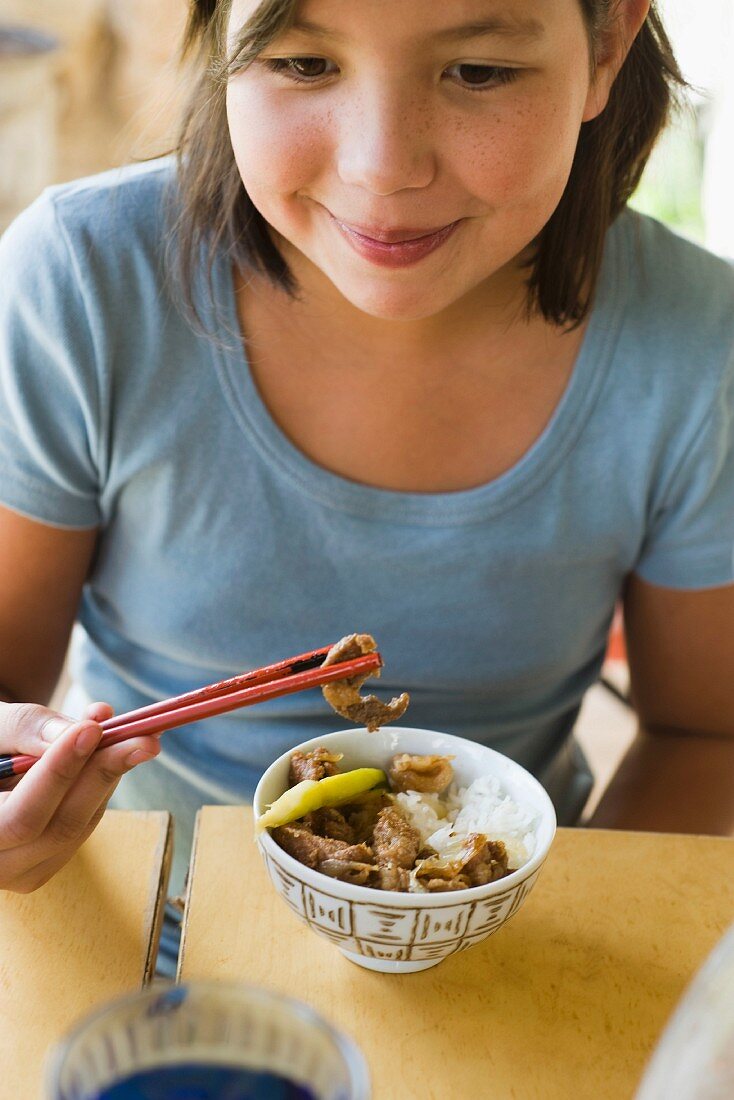 A girl eating prawns with rice