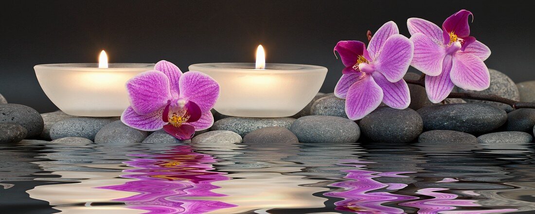 Relaxation in spa - tea lights and orchid flowers reflected in water