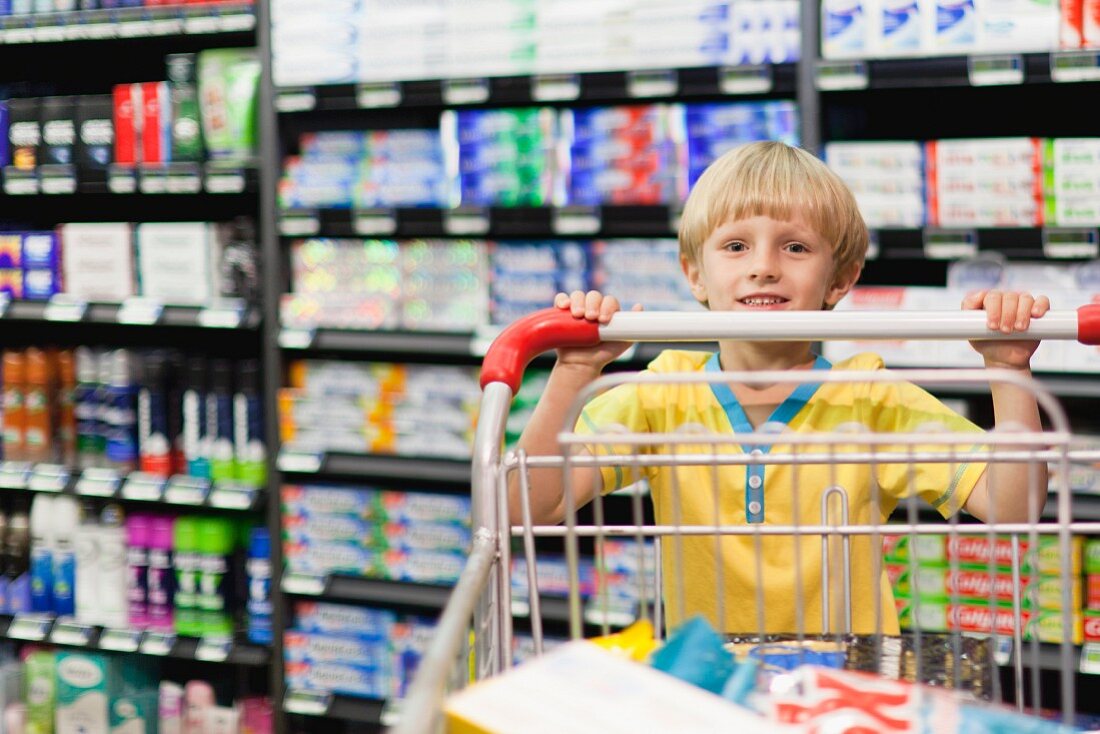 A little boy with a shopping trolley in a supermarket