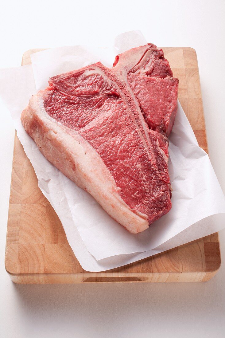 T-Bone-Steak mit Papier auf Holzbrett