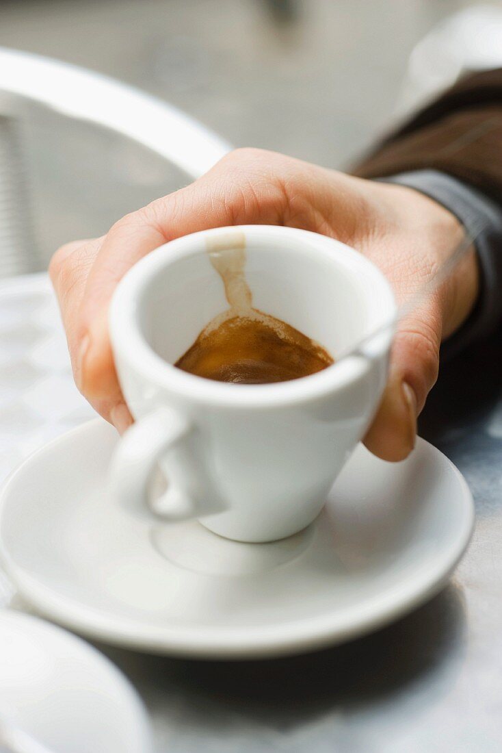 A hand holding an espresso cup