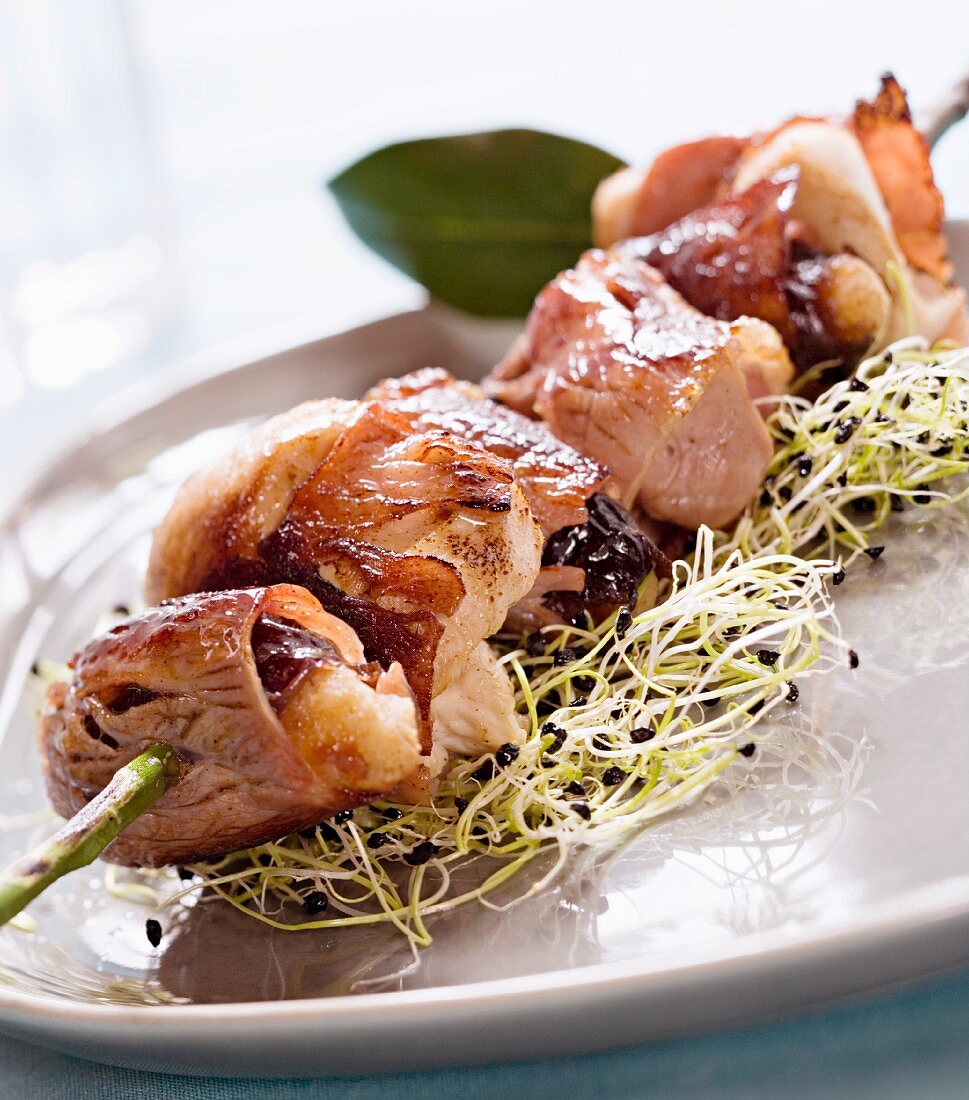 Chicken kebab with bacon and dried plums on a bed of bean sprouts