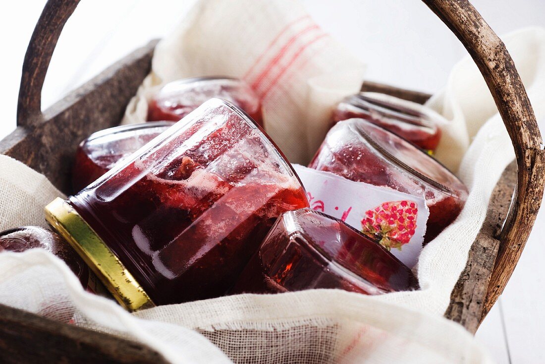 Jars of strawberry jam in a wooden basket