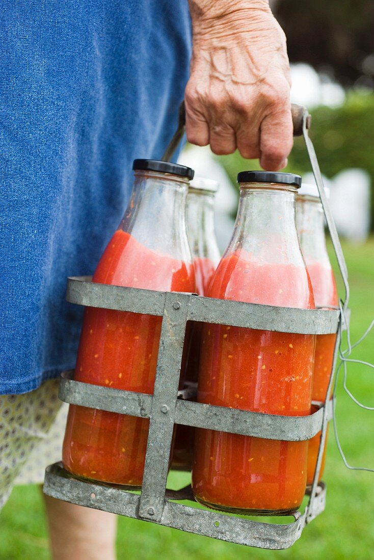 Bäuerin trägt Flaschen mit Tomatenpüree