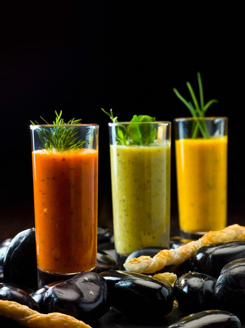 Drei verschiedene Gemüsesuppen im Glas, dazu Käsestangen