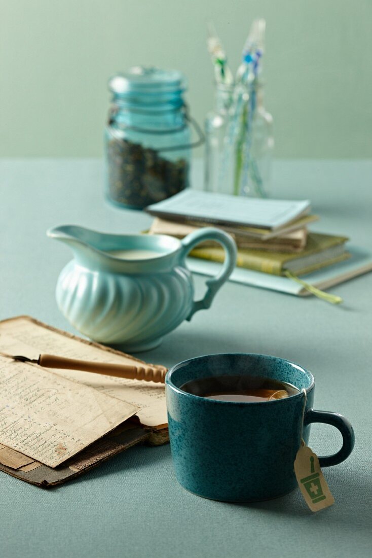 Eine Tasse Marihuanatee, alte Bücher und Sahnekännchen