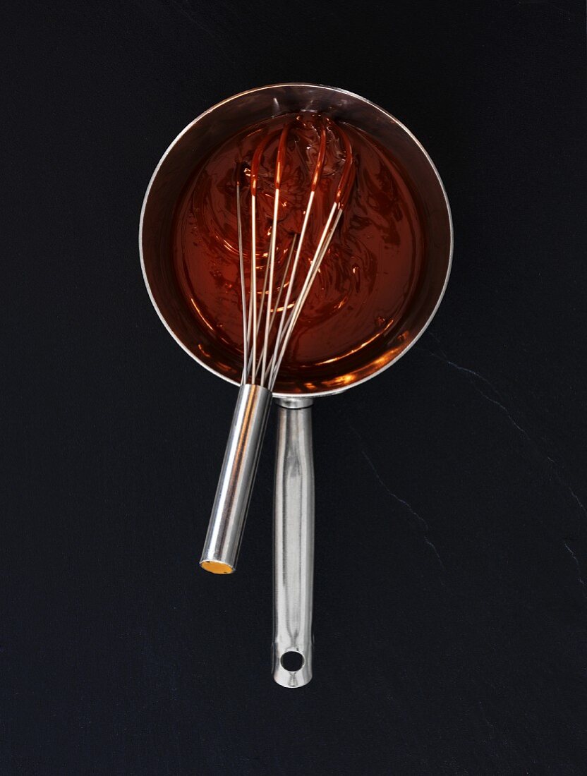 Liquid chocolate in a saucepan with a whisk (seen from above)