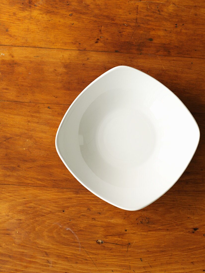 A white porcelain bowl on a wooden surface (seen from above)
