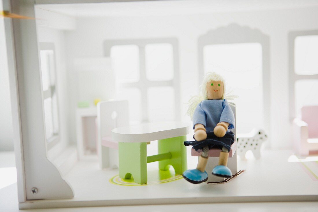 Doll sitting in chair in doll house