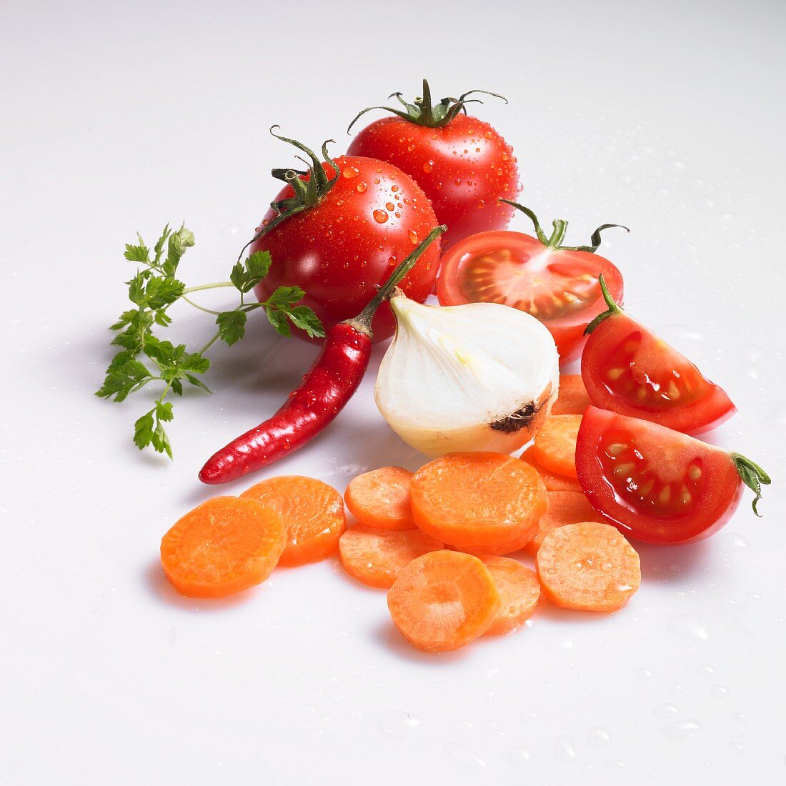 Möhrenscheiben, Zwiebel, Tomaten, Chilischote und Kerbel mit Wassertropfen