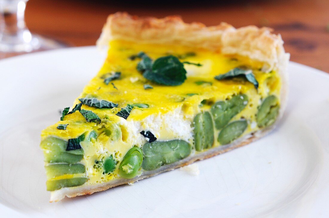 A slice of ricotta and broad bean quiche on a plate