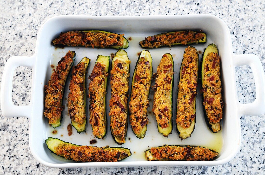 Courgettes filled with bacon, cheese and breadcrumbs in a baking dish