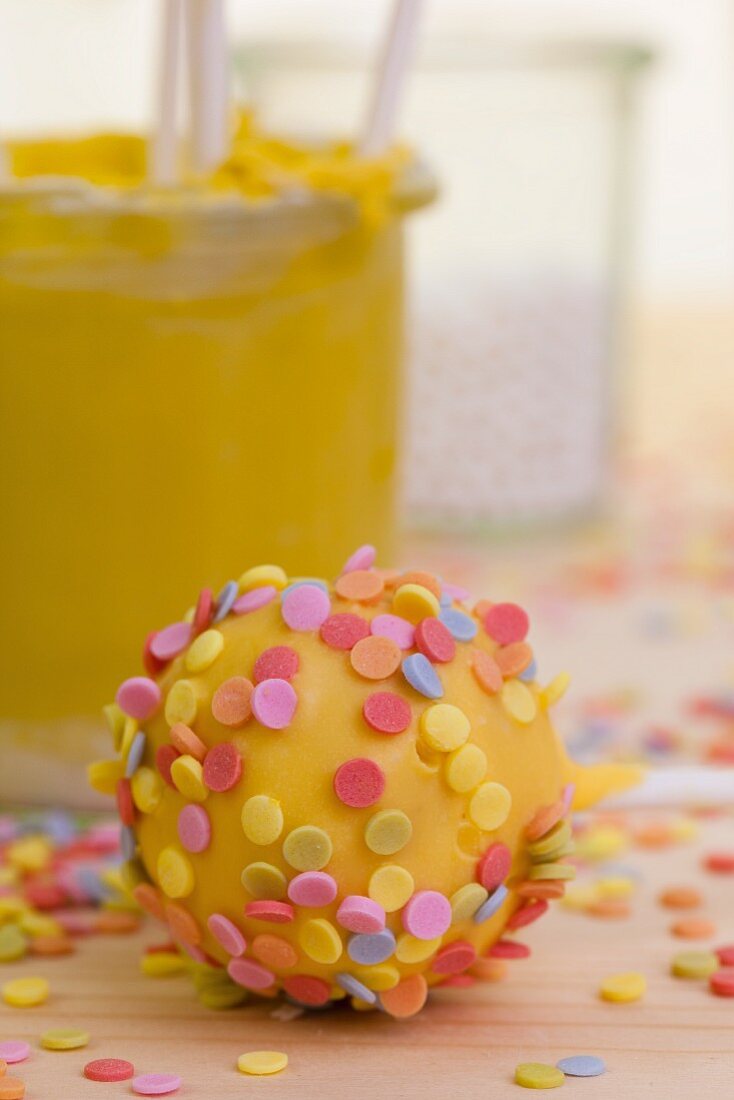 Viele bunte Zuckerstreusel auf einem gelben Cake Pop