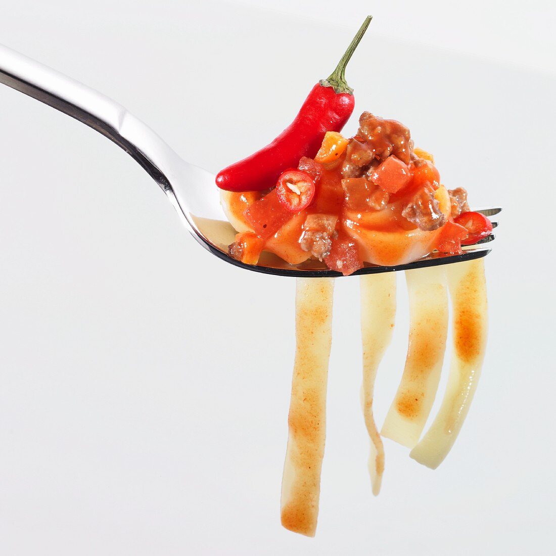 Gabel mit Bandnudeln, scharfer Tomaten-Hackfleisch-Sauce und Piri-Piri-Schote