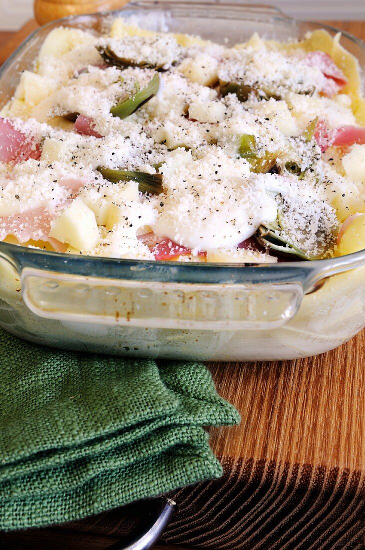 Unbaked lasagne with artichokes and ham in a baking dish