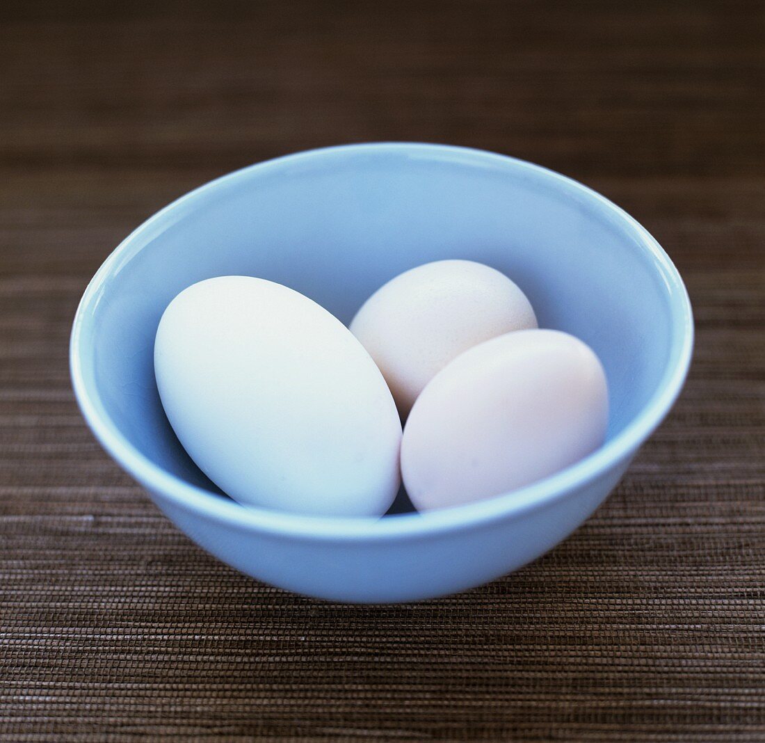 Three white eggs in a bowl