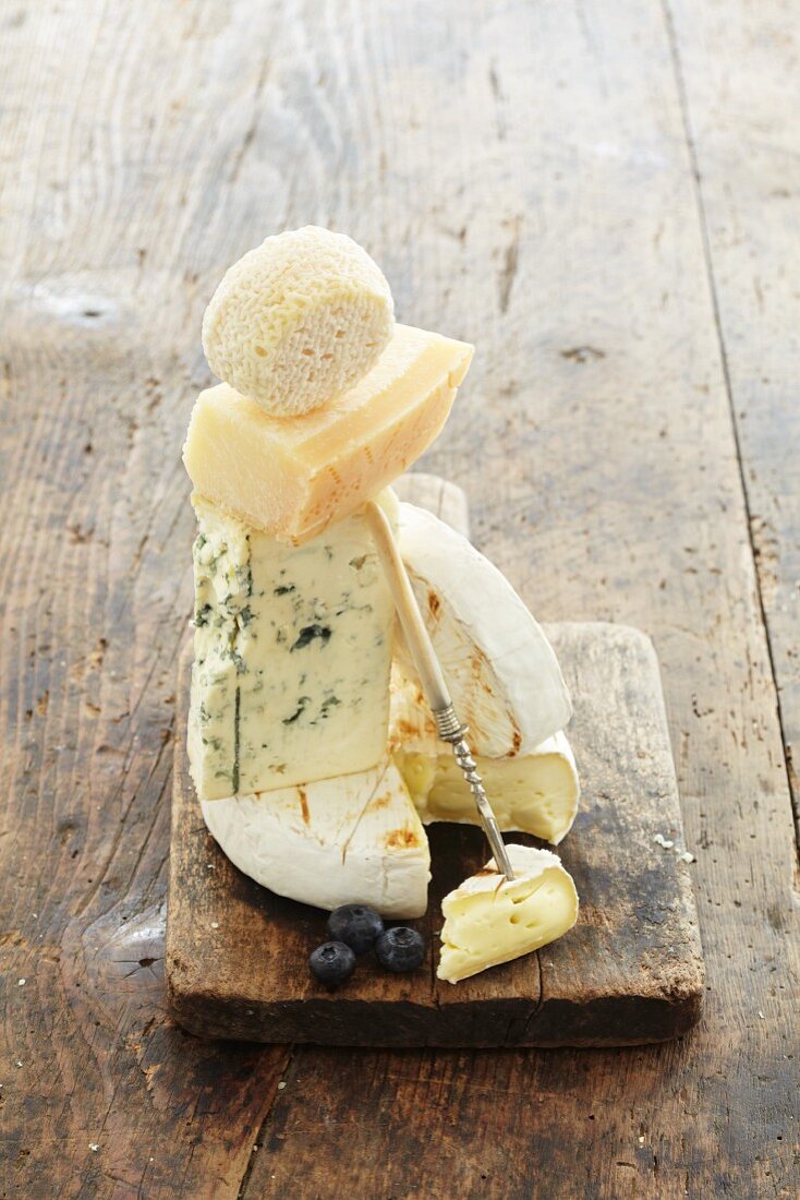 A stack of various cheeses on chopping board