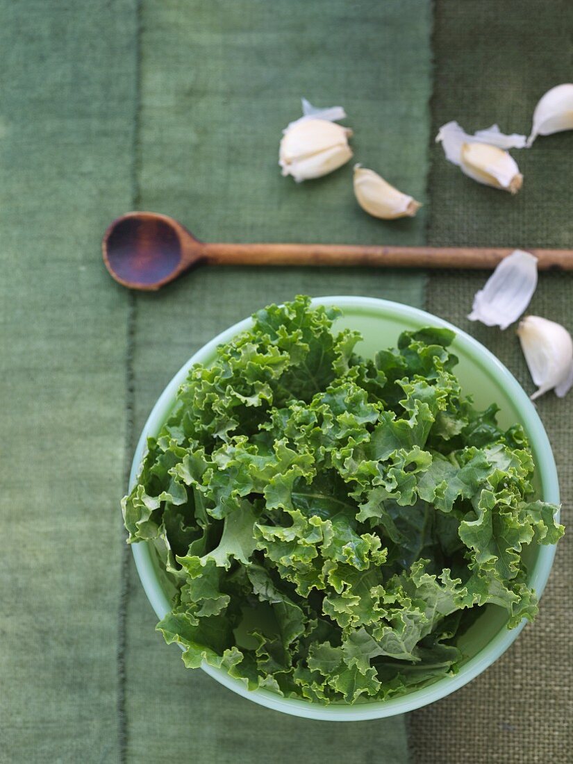 Fresh Kale in a Bowl; From Above; Garlic and Wooden Spoon