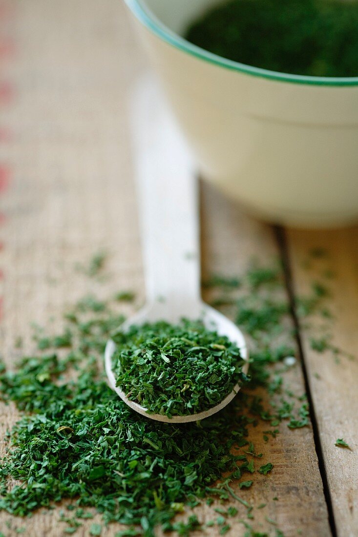 Dried parsley on a wooden spoon and a bowl