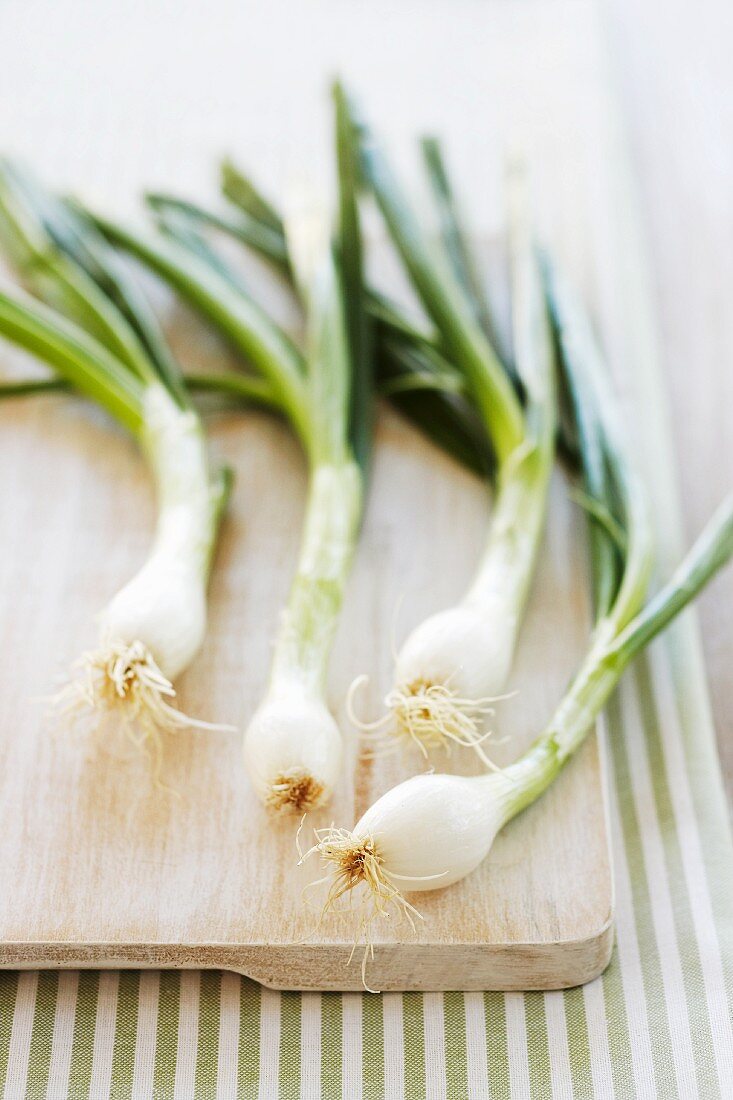 Four spring onions on a chopping board