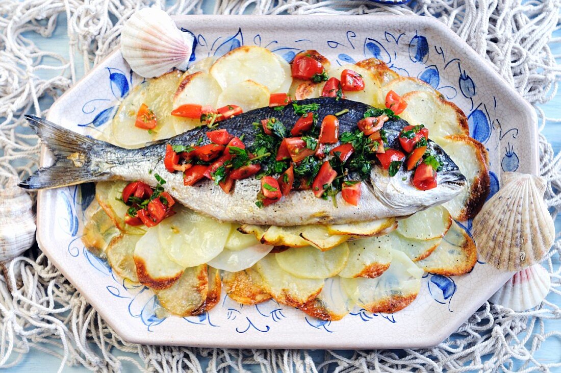 Roasted whole sea bream on a bed of potatoes with a fresh tomato dressing
