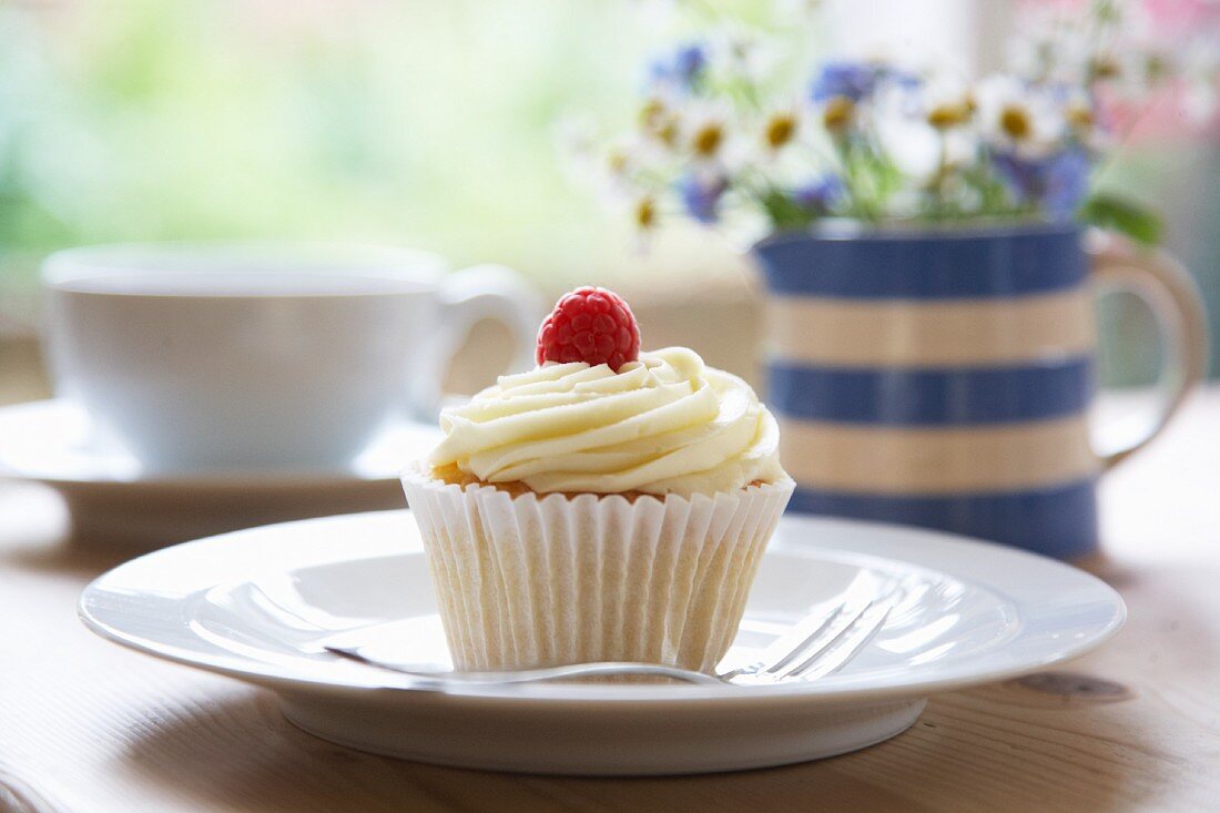 A white chocolate cream and raspberry cupcake