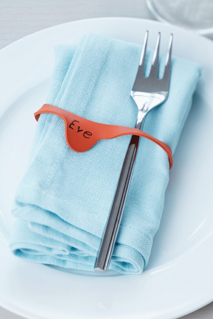 Place setting with name written on napkin ring made from preserving jar rubber seal