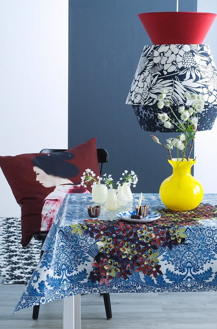 Black and white pendant lamp with floral pattern above dining table and Geisha cushion on chair