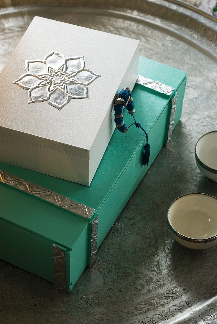 White and green painted wooden boxes ornamented with metal details on Oriental metal tray