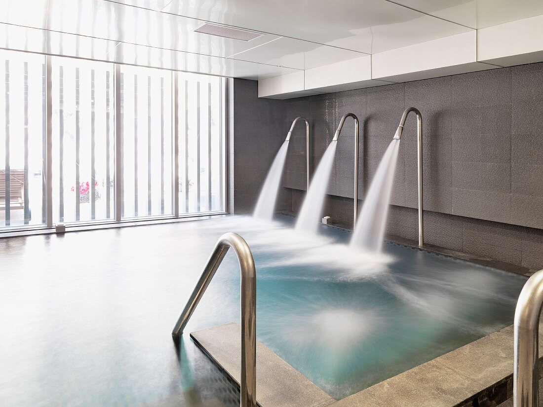 Cascade showers spouting into indoor pool in contemporary building