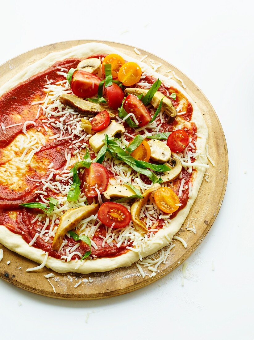 Pizza mit Kirschtomaten, Pilzen, Basilikum und Parmesan (ungebacken)