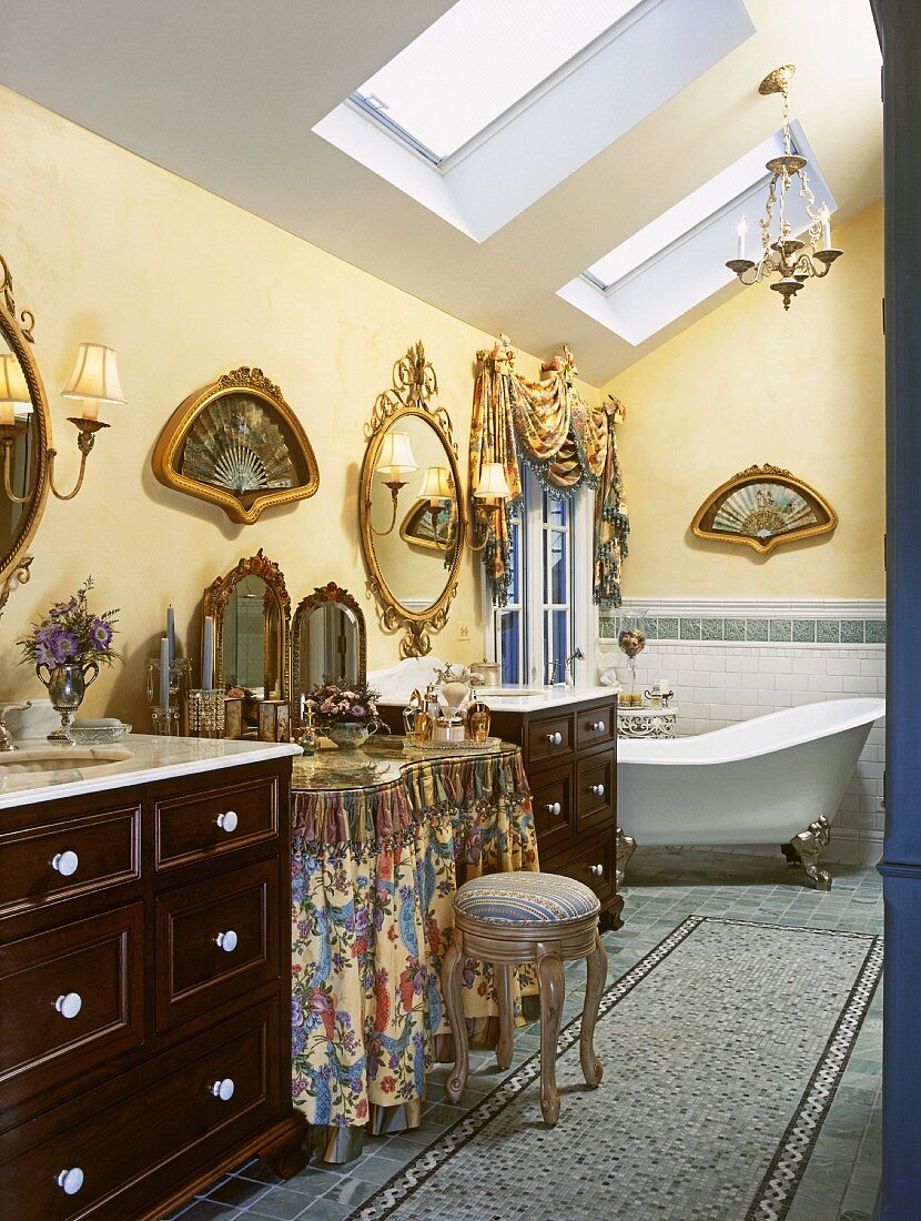 Ornate attic bathroom with free-standing bathtub and gilt-framed, fan-shaped pictures on walls