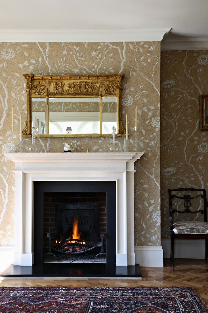 Traditional living room with open fireplace below mirror on wall with stencilled patterns