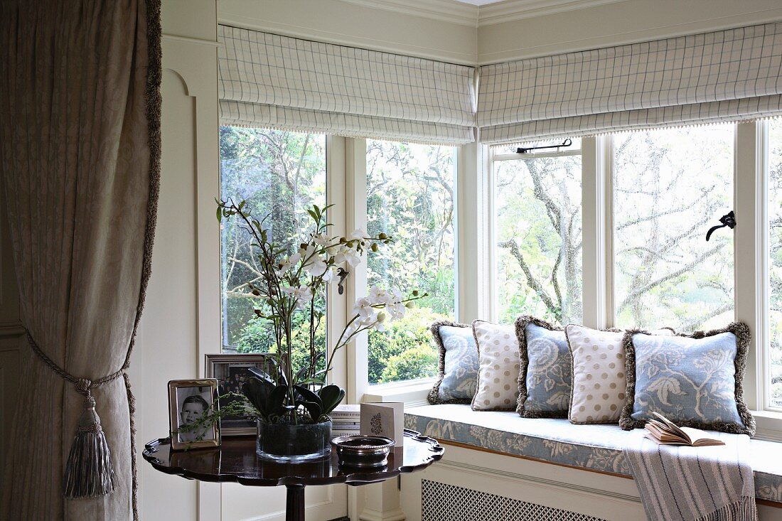 Comfortable window seat with a view and potted orchid on side table
