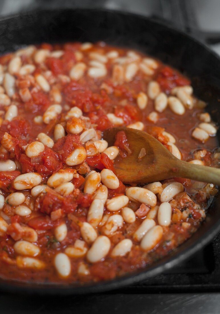 White beans, tomato and bacon in a pan
