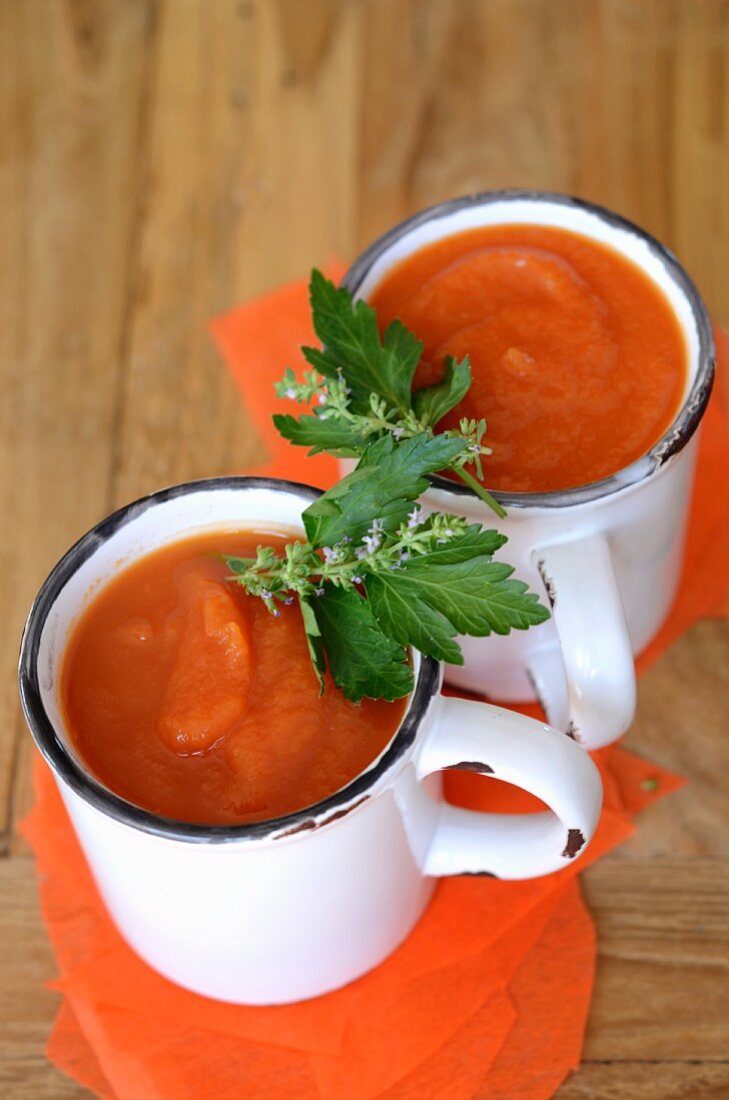 Cold carrot and tomato soup in enamel mugs