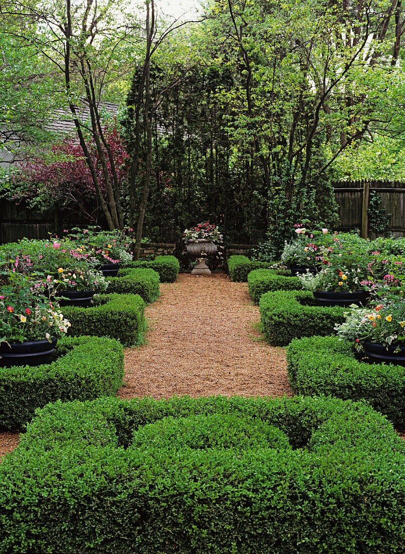 Gepflegter Park mit großen Blumenkübeln und säuberlich geschnittenen Hecken