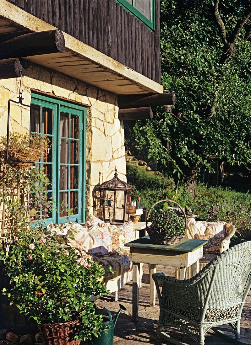 Sonnenterrasse eines Natursteinhauses; gemütich gestaltet mit Vintagemöbeln und Blumentöpfen