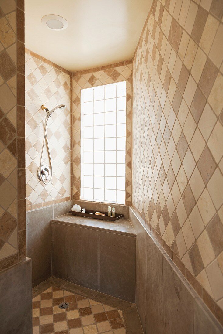 Bathroom tiles on walls and floor in various shades of brown laid diagonally