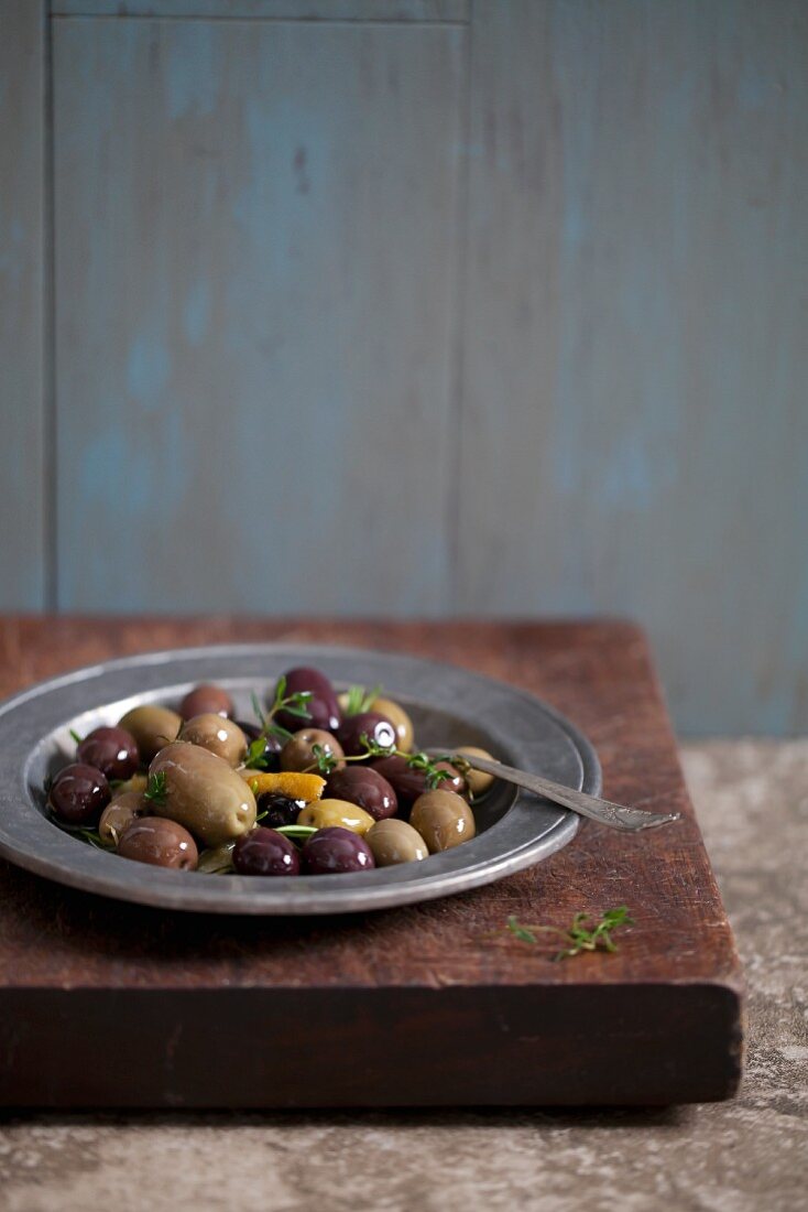 Verschiedene eingelegte Oliven mit Thymian auf Teller