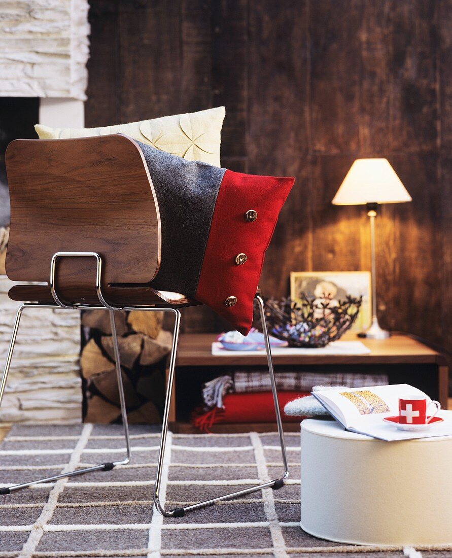 Cushions on wooden chair with chrome frame in front of fireplace