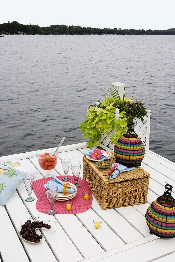 Picnic preparations on white-painted wooden jetty on lake shore