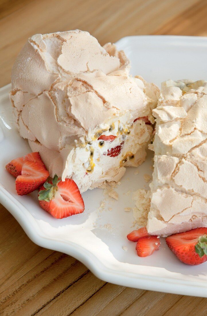 Meringue roulade with cream, strawberries and passion fruit