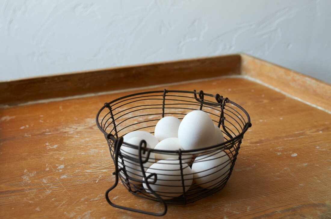 Eggs in a wire basket on a wooden tray
