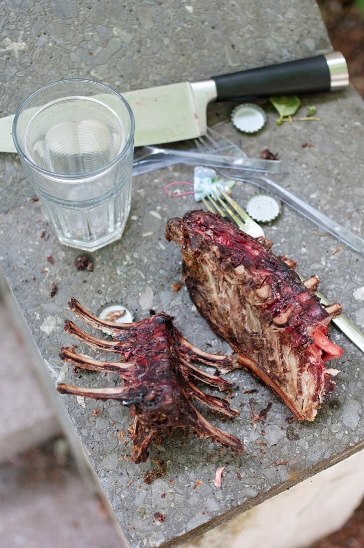 The remains of spareribs with a knife and a drinking glass